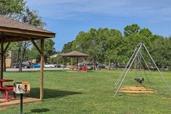 A playground with a swing set and picnic table.